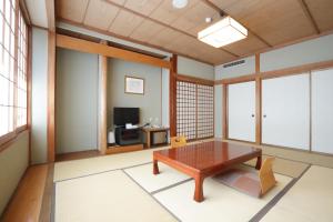 a living room with a wooden table and a television at Taiheikan in Fujikawaguchiko