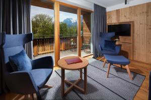 a living room with two blue chairs and a television at Hotel Hindenburglinde in Ramsau