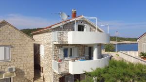 a stone house with a white balcony and the ocean at Apartment Karuza Rukavac in Vis
