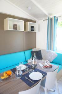 a dining room with a table and a blue couch at Camping de l'île in Bannay