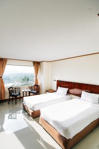two beds in a hotel room with a large window at Sinkiat Thani Hotel in Satun