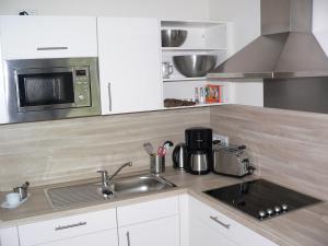 eine Küche mit einer Spüle und einer Mikrowelle in der Unterkunft Nordsee Domizil Schobüll in Husum