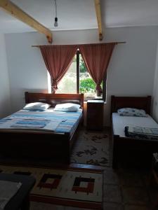 1 dormitorio con 2 camas y ventana en Eco Garten Guest House, en Shkodër