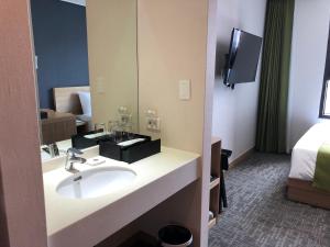 a bathroom with a sink and a mirror and a bed at Hotel Kuretakeso Insadong in Seoul