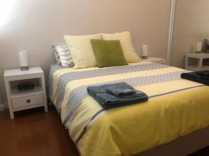 a bedroom with a bed with a green and yellow blanket at Allora Apartment Applecross in Perth