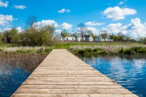 a wooden bridge over a river with houses in the background at Erne View Cottages in Lisnaskea