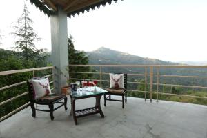 a table and two chairs on a balcony with a view at The Moksh Eco Inn in Mukteswar