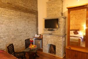 a living room with a stone fireplace with a television at The Moksh Eco Inn in Mukteswar