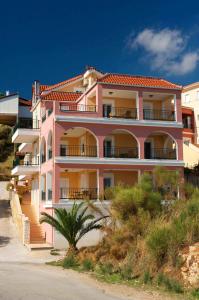 a pink building with a palm tree in front of it at Mari-Christi Apartments in Poros
