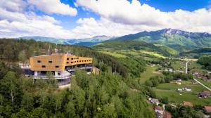a building on a hill with mountains in the background at Tarcin Forest Resort and Spa MGallery by Sofitel in Tarčin
