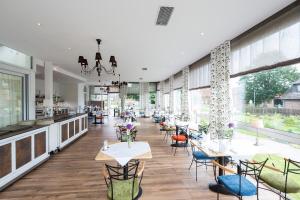 um restaurante com mesas e cadeiras e janelas grandes em Parkhotel Bilm im Glück am Stadtrand Hannovers em Sehnde