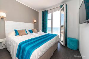 a bedroom with a large bed with a large window at Hôtel George Sand in La Seyne-sur-Mer