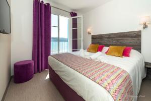 a bedroom with a large bed with purple curtains and a window at Hôtel George Sand in La Seyne-sur-Mer