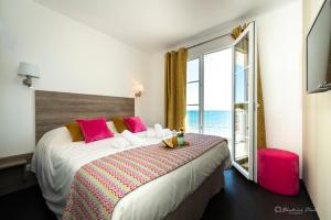 a bedroom with a large bed with a large window at Hôtel George Sand in La Seyne-sur-Mer