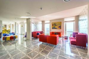 un vestíbulo con sillas rojas, mesas y ventanas en Grand Hotel Miramare, en Taormina