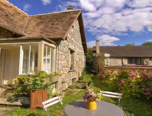 a stone house with a table and chairs in the yard at Les Rouges Gorges in Giverny