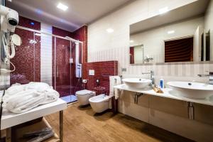 y baño con 2 lavabos, ducha y aseo. en Hotel Terre Dei Salici, en Caramagna Piemonte
