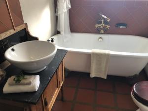 a bath tub sitting next to a sink in a bathroom at Dio Dell Amore Guest House in Jeffreys Bay