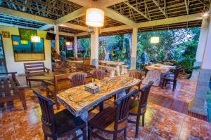 un restaurante con mesas de madera y sillas en una habitación en Lotus Garden Huts en Lembongan