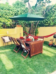 a wooden table with a green umbrella on the grass at BS Villas Porto in Porto