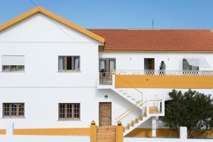 a person standing on the balcony of a white building at Ondina Guesthouse in Casais de São Lourenço
