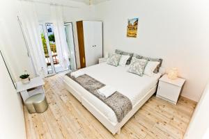 1 dormitorio blanco con 1 cama y suelo de madera en Apartments Ana I, en Hvar