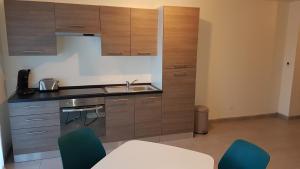 a kitchen with wooden cabinets and a sink and blue chairs at Amnéville centre touristique in Amnéville