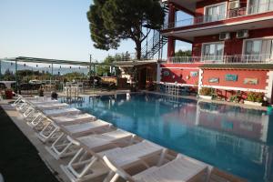 a row of lounge chairs sitting next to a swimming pool at Tunc Hotel in Ayvalık