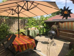 eine Terrasse mit einem Tisch, einem Sonnenschirm und einem Grill in der Unterkunft Blanks Safari Lodge in Klein Schwaß