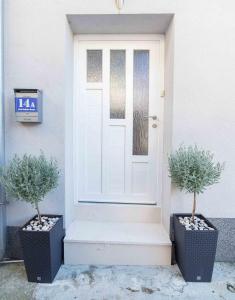 una porta bianca con due piante in vaso accanto di Apartments Tonka Centar a Vodice
