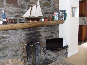 Elle comprend une cheminée en pierre avec une télévision et un bateau. dans l'établissement Inglenook, à Kinsale