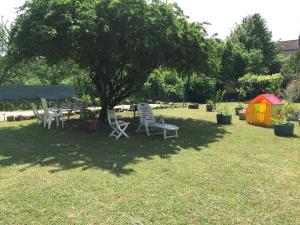 twee stoelen en een tafel onder een boom in een tuin bij Villa Roland en Bourgogne in Chagny
