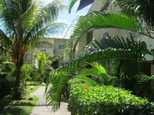 un jardín con palmeras y arbustos junto a un edificio en Home Sweet Home, en Flic en Flac