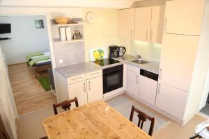 a kitchen with white cabinets and a wooden table at Pro's Apartment in Hermagor