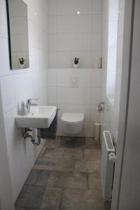 Haus Kornblume في Oberlangen: حمام أبيض مع حوض ومرحاض