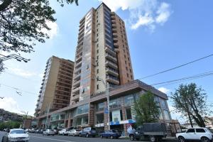 un edificio alto en una calle de la ciudad con coches aparcados en Sayat Nova Apartment, en Ereván