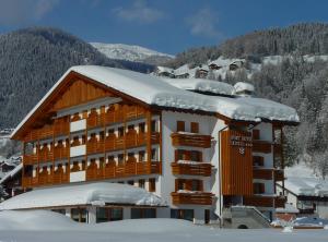 a large building with snow on the roof at Sport Hotel Cristal in Falcade