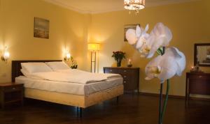 グダニスクにあるKobza Haus Old Townのベッドルーム1室(白いシーツと花のベッド付)