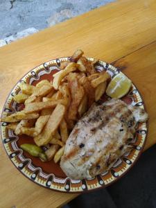 um prato de peixe e batatas fritas numa mesa em Guest House Todorini kashti em Koprivshtitsa