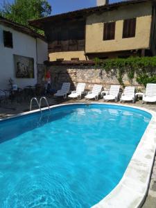 a large swimming pool with chairs and a house at Guest House Todorini kashti in Koprivshtitsa