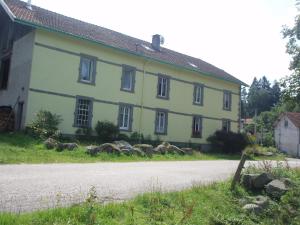 une maison jaune avec une route devant elle dans l'établissement FERME DU HAUT BARBA chambres d'hôtes & gîte, à Liézey