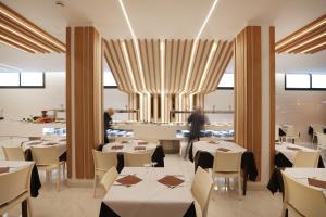 Hotel Brasil في بنيدورم: مطعم بطاولات بيضاء وكراسي بيضاء وشخص