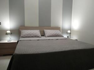 een slaapkamer met een groot bed met 2 lampen bij Via Roma 12 in Messina