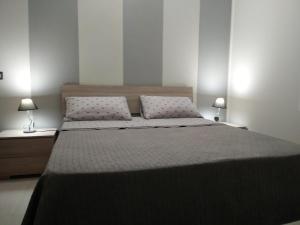 une chambre avec un grand lit avec deux lampes dans l'établissement Roma 12, à Messina