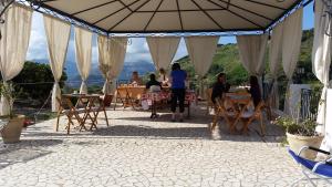 un grupo de personas sentadas en mesas bajo un paraguas en B&B Villa Maristella en Lipari