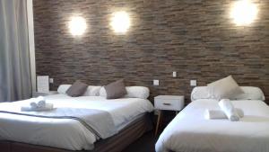 two beds in a room with a brick wall at Le Relax in Aurillac