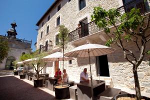 un groupe de personnes assis sous des parasols à l'extérieur d'un bâtiment dans l'établissement Urban Style LES FLEURINES, à Villefranche-de-Rouergue