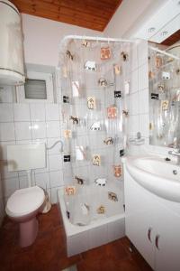 a bathroom with a shower curtain with a toilet and a sink at Apartments Niko Metajna, island Pag in Metajna