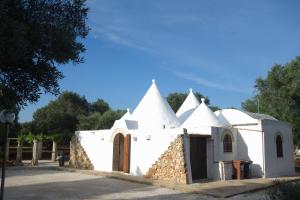 a white church with trees in the background at Trulli Monte Madre in San Vito dei Normanni