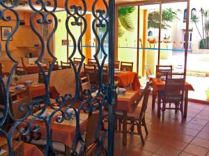 um restaurante com mesas e cadeiras de madeira e uma cerca em Hotel Alhambra em Cap d'Agde